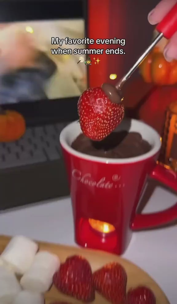 Dipping a strawberry into melted chocolate in the red fondue mug during a movie night
